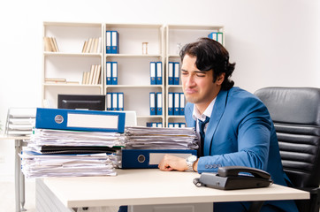 Young handsome busy employee sitting in office 