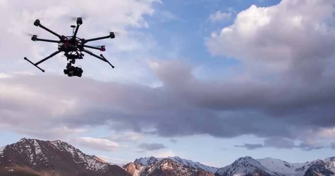 Rise Research Drone. Radio controlled hexacopter rises into the air from the ground position on the background of snowy mountains