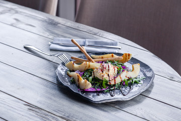 Closeup fresh diet salad with goat cheese, pear, Chinese cabbage, arugula, bread sticks, balsamic dressing, serving fork, knife, restaurant. Concept professional food shooting, photosession new menu