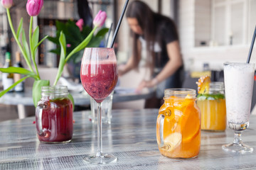 Food stylist and photographer decorate, preparing to shoot various cocktails, milkshakes, smoothies, flower tulips in vase on table. Concept professional photography, photo session new menu, freelance