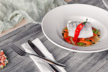 Closeup fillet stewed pike perch with vegetables, chilli pepper, tomato, onion, mini carrot with...