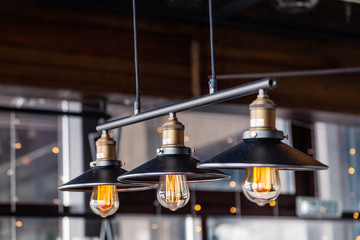 Fototapeta na wymiar Black iron loft chandeliers with edison lamps on a black background, bokeh. Concept of modern interior design of restaurant, cafe, apartment, office, shop, wine bar