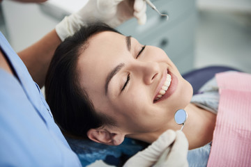 Fototapeta na wymiar Charming young woman with straight white teeth visiting dentist
