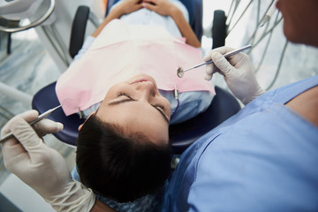 Smiling young lady receiving teeth treatment in modern dental clinic