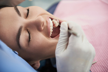 Charming lady with closed eyes being examined by doctor at dental clinic