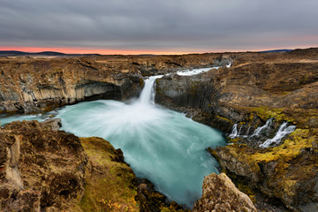 Aldeyjarfoss waterfall in Iceland at sunrise with golden clouds in the sky. Amazing landscape in beautiful tourist attraction. Wonder of nature with glacier water.