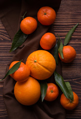 Ripe delicious mandarines with zest on dark wooden table