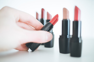 Obraz premium Taking a lipstick: Female hand is taking an elegant, red lipstick