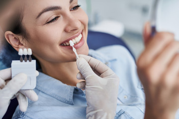 Male dentist choosing color for woman teeth