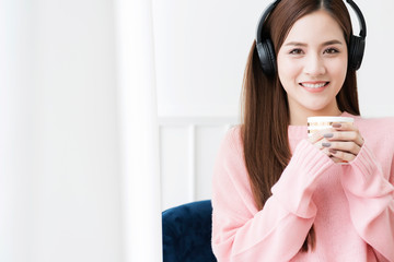 beautiful attractive asian woman pink sweater casual moment with headphone and hot drink at home weekend vacation