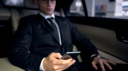 Fototapeta na wymiar Serious businessman using phone in car, app for analyzing traffic jams in city