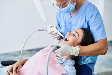 Beautiful young woman sitting in dentist chair during dental procedure