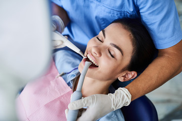Fototapeta premium Charming young woman having dental procedure at modern clinic