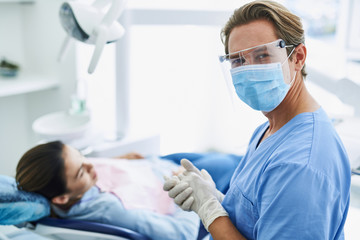 Handsome dentist in protective mask feeling satisfied after dental procedure