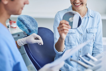 Smiling young lady estimating results of dental treatment