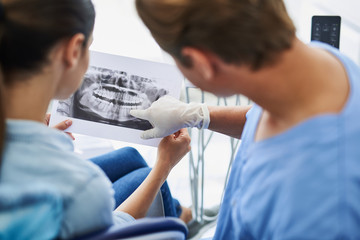 Dentist showing results of orthopantomogram to young lady