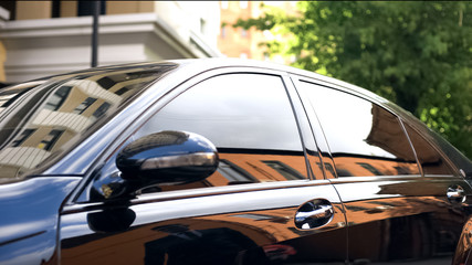 Luxury car with tinted glass standing at parking, reflection of businessman - Powered by Adobe