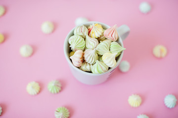 Obraz na płótnie Canvas A cup of homemade mini meringues on pink background.