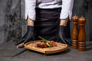 Chef in hotel or restaurant kitchen cooking only hands. Prepared beef steak with vegetable decoration