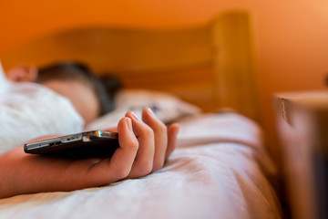 Sleeping teenage boy holding hes smartphone, conceptual image of smartphone addiction.