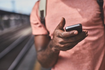 Afro-american man using smartphone on train station