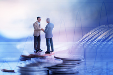 Double exposure row of coins of Two Business man and graph,saving,investment and finance concepts. Miniature people Stand ,soft focus and blurred style.