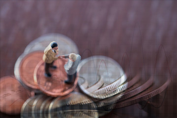 Double exposure row of coins of Two Business man and graph,saving,investment and finance concepts. Miniature people Stand ,soft focus and blurred style.
