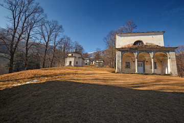 Fototapeta na wymiar Panoramic view in the afternoon light on a winter day, of the seventeenth-century chapels of the monumental complex dedicated to the Virgin Mary, of the Sanctuary of Oropa in Piedmont, Italy.