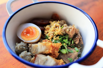 Thai rice porridge breakfast served with topping such as pork meatballs, fried onions, garlic, egg, green onions, and cilantro.