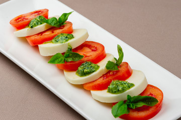 salad with fresh tomatoes, cheese and greens on a white plate