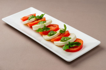salad with fresh tomatoes, cheese and greens on a white plate