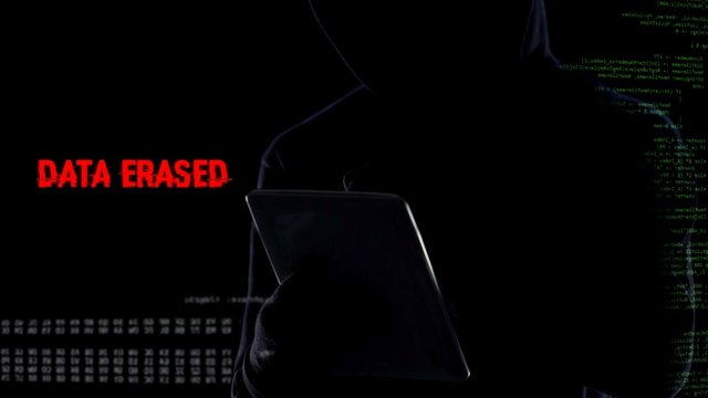 Faceless hacker cracking password and erasing all files database using tablet