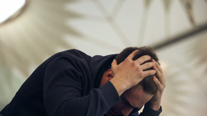 Young male holding head, suffering from hangover after night party, vomiting