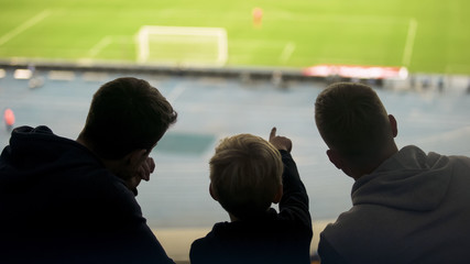 Father and two sons watching football match together, happy weekend, fatherhood