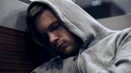 Fototapeta premium Homeless man in hoodie sleeping in public transport, unemployment problems