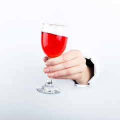 Female hand out of the hole in the paperman, holding a glass of red wine. Isolate on white background.