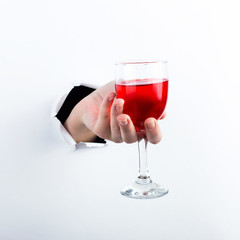 Female hand out of the hole in the paperman, holding a glass of red wine. Isolate on white background.