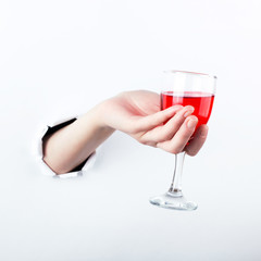 Female hand out of the hole in the paperman, holding a glass of red wine. Isolate on white background.