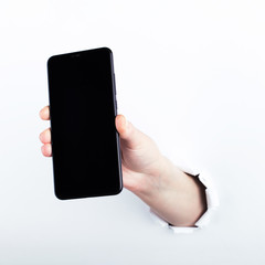Female hand out of the hole in the paperman, holding a smartphone with a black screen. Isolate on white background.