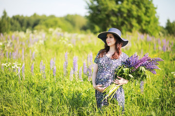 Pregnant girl in a field with lupines