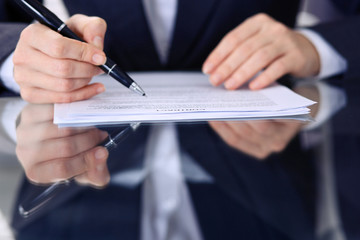 Unknown female hands with pen over document of contract. Agreement signing or business concept