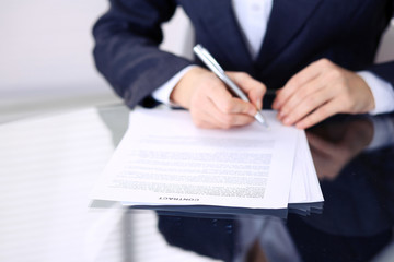 Unknown female hands with pen over document of contract. Agreement signing or business concept