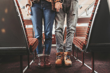 Waist down of hipster beloved couple in bus cafe