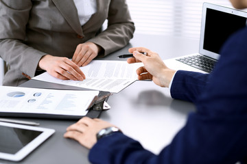 Business people and lawyer discussing contract papers sitting at the table, hands close-up. Teamwork or group operations concept