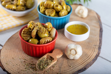 Wooden background with green olives, olive oil, garlic and spices