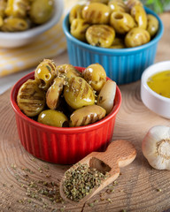 Wooden background with green olives, olive oil, garlic and spices