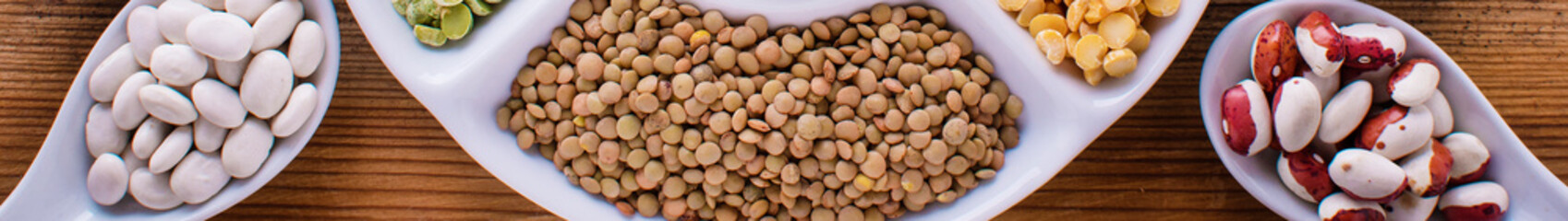 Various assortment of legumes - beans, soy beans, chickpeas, lentils, green peas. Top view banner format