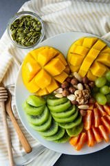 Delicious fruits platte isolated. Mango, kiwi, citrus, nuts, grapes. Mix of various exotic fruits. Healthy fruit salad, healthy lifestyle.