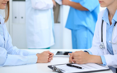 Doctor and patient discussing something, just hands at the table, white background
