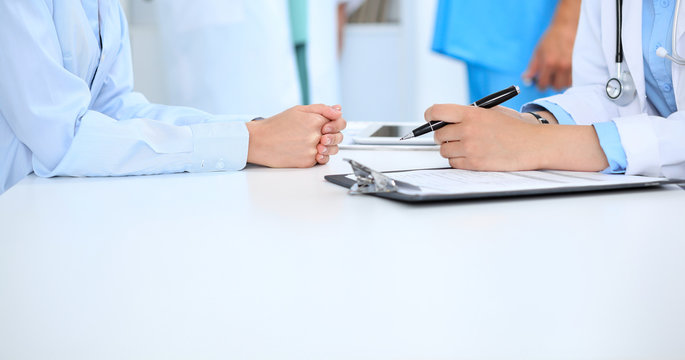 Doctor and patient discussing something, just hands at the table, white background